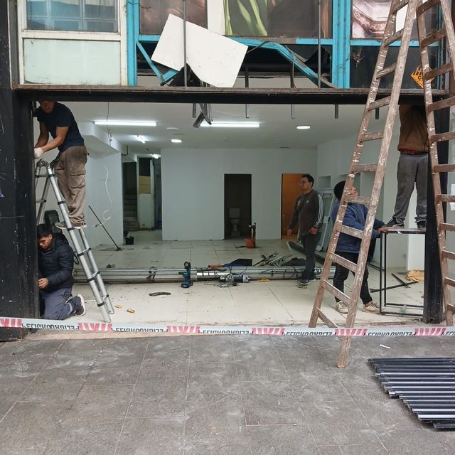 Equipo instalando una cortina metálica en un local comercial vacío